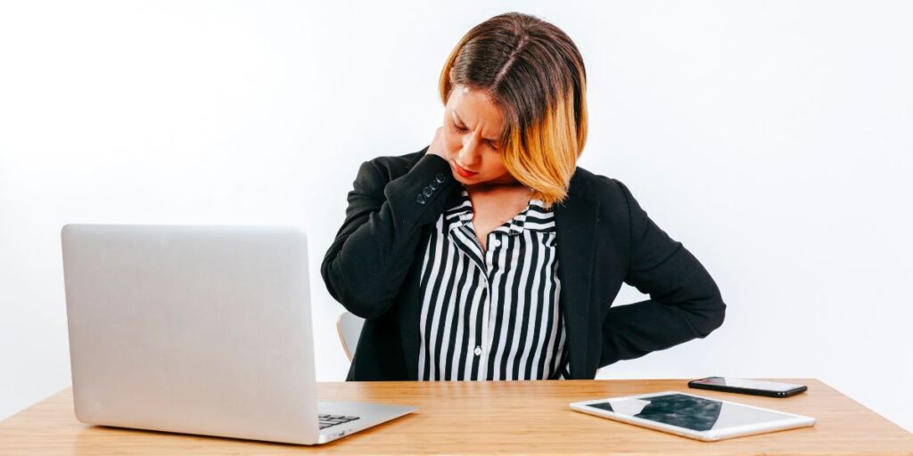Women suffering from neck pain in front of desktop in office